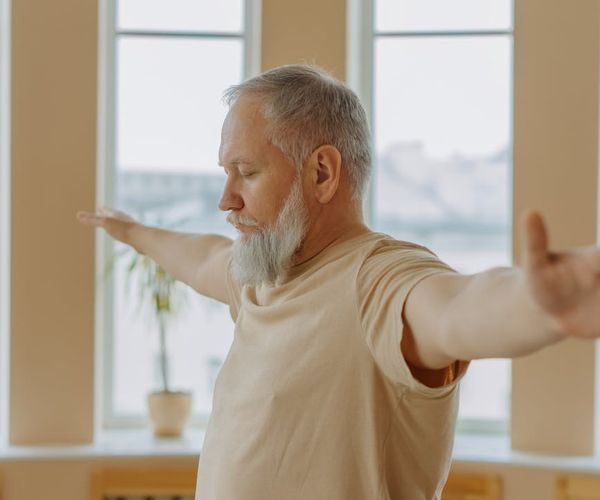 Person stretching gently near a window at sunrise.